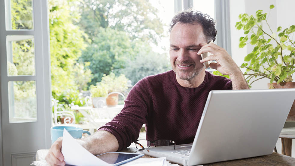 Working from home; man smiling on the phone